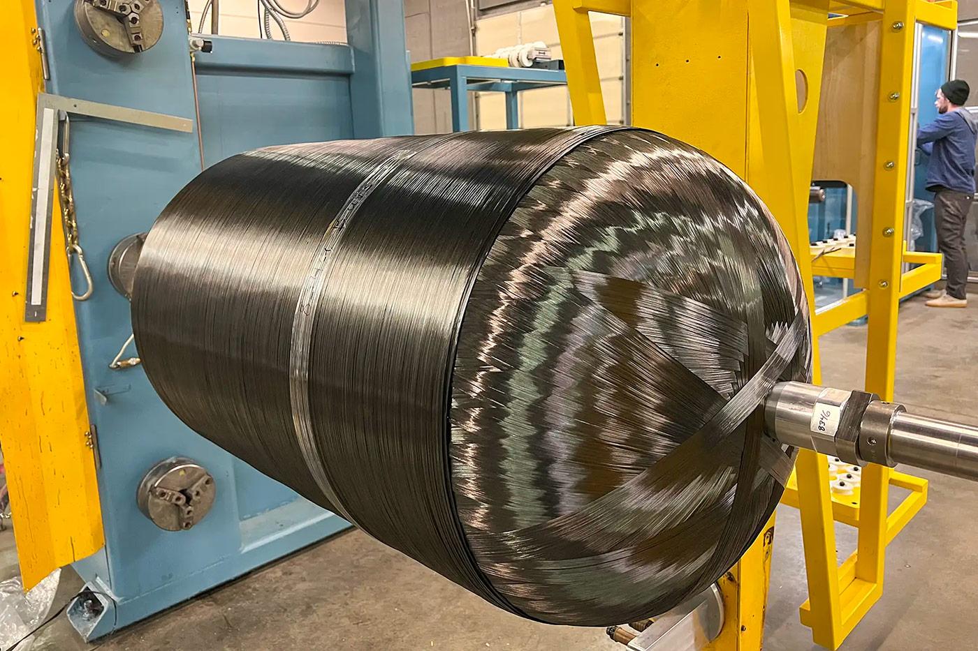 Composite fiber overwrapping in progress on a cylindrical tank during manufacturing, illustrating Steelhead’s process for converting heavy metal tanks into lightweight, high-strength composite pressure vessels for fleet efficiency.