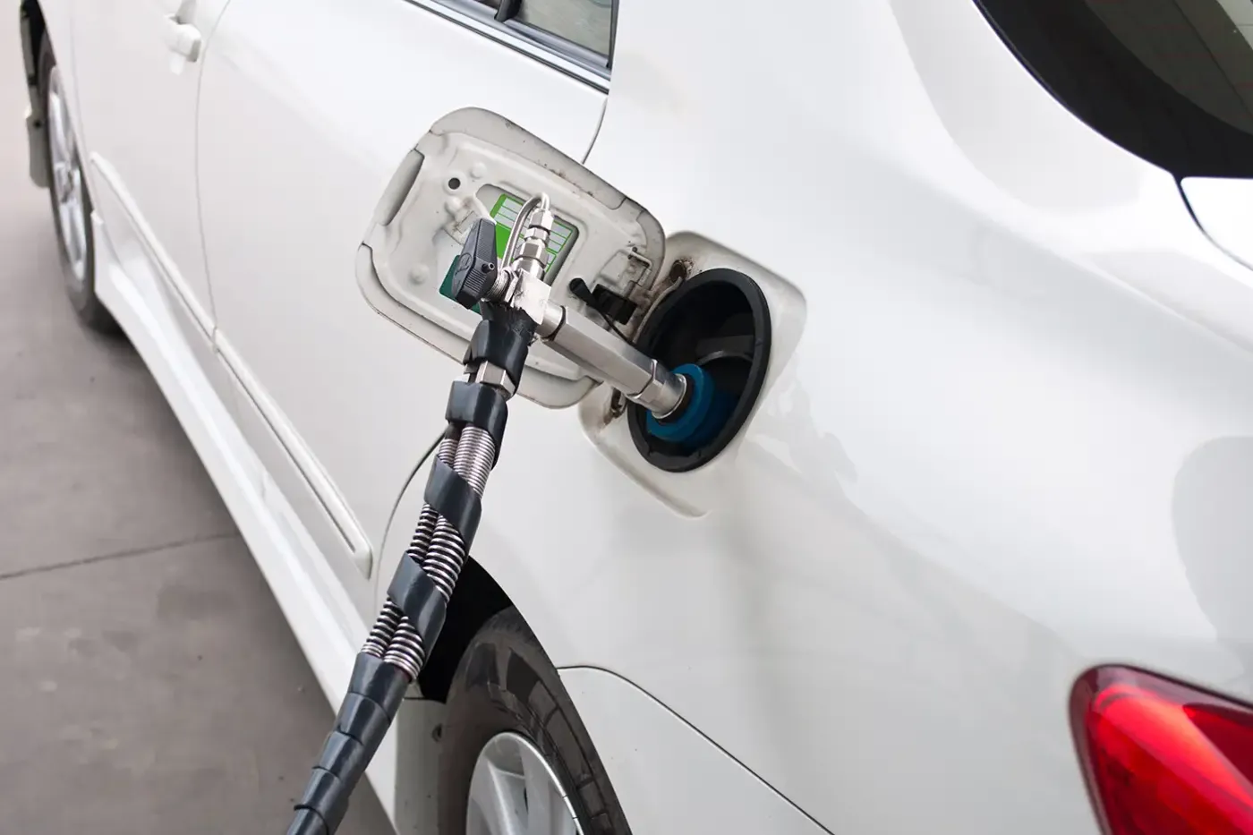 CNG vehicle refueling: Steelhead Composites clean energy application with a compressed natural gas (CNG) fueling nozzle connected to a white vehicle at a refueling station.